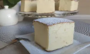 Puszysty sernik wiedeński z wiaderka, oprószony cukrem pudrem, czeka na widelczyk.