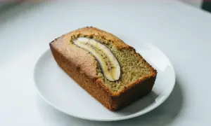 Pyszny chlebek bananowy z plasterkiem banana na wierzchu, podany na białym talerzyku.