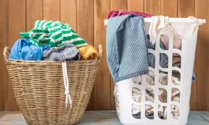 Zwei Wäschekörbe, einer aus Weide, der andere weiß, gefüllt mit Kleidung. Grüne und weiße Streifen, Blau und Gelb. Die Frage ist, welche Farben zusammen waschen.