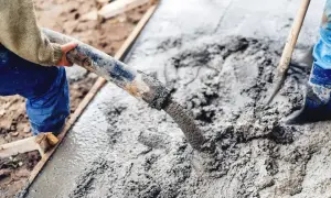 Pracownicy wylewają świeży beton. Właściwe suchy beton proporcje są kluczowe dla trwałości konstrukcji.