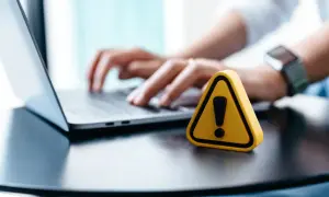 Żółty trójkąt z wykrzyknikiem obok laptopa, sugerujący problem, dlaczego nie mogę wylogować się z Facebooka.