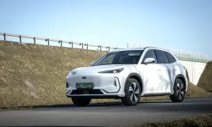 Biały Geely EX5 na tle nieba i nasypu drogowego. Elegancki SUV gotowy na podróż.