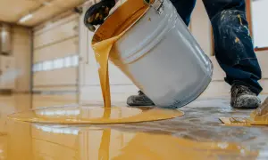 Vertiendo pintura epoxi amarilla sobre un suelo. Las opiniones sobre la pintura epoxi para azulejos son muy positivas.