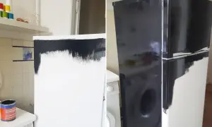 En burk med svart färg står bredvid en tvättmaskin. Kylskåpet är halvmålat i svart, en del av arbetet med att måla kylskåp.