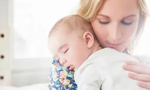 Samotna matka tuli śpiące dziecko. Delikatne światło otula ich spokój.