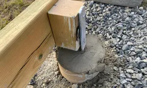 Nygjuten betong runt en stolpe som ska bära en altan. Plintavståndet är viktigt för stabiliteten.