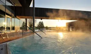 Dampf steigt aus einem Pool auf, während die Sonne über Brandenburg aufgeht. Ein perfekter Ort für einen erholsamen Urlaub.