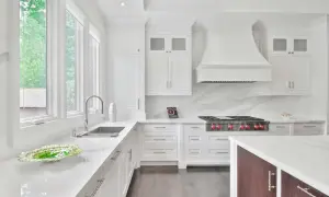 Cocina moderna blanca con encimeras de cuarzo. Muebles de cocina de melamina con tiradores plateados. Campana extractora y estufa profesional.