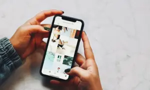 Dłonie trzymające telefon, na ekranie widoczny profil Instagrama z moimi pracami. Niestety, moje urządzenie iPhone niedostępne.