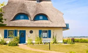 Charmantes Haus mit Reetdach und blauen Akzenten. Ein Blick auf die Frage: was kostet ein reetdach?