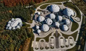 Architektoniczny kompleks przypominający alvernia planet, z kopułowymi budynkami otoczonymi lasem i parkingiem.