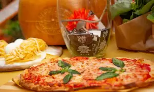 Pyszna pizza na stole, obok makaron i ser. Zastanawiasz się, pizza mrożona ile piec? Sprawdź instrukcję na opakowaniu!