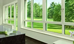 Amplias ventanas prefabricadas PVC con vistas a un exuberante jardín verde.