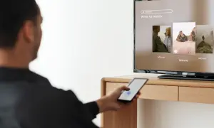 Mężczyzna steruje telefonem, by dowiedzieć się, jak udostępnić internet z telefonu na telewizor i oglądać filmy.