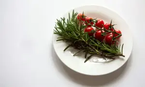 Gałązka rozmarynu z pomidorkami koktajlowymi na białym talerzu. Rozmaryn do czego? Do aromatycznych potraw!