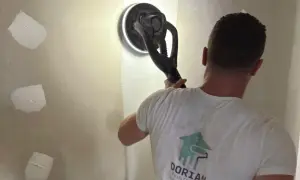 Un artisan utilise une ponceuse girafe pour lisser un mur en placo. C'est la ponceuse idéale pour un travail de finition impeccable.