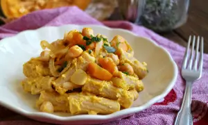Piatto di pasta con la zucca, ceci e cipolla, guarnito con prezzemolo fresco. Un comfort food autunnale.
