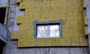 Pannelli isolanti gialli applicati al muro grezzo di un edificio in costruzione, creando un cappotto casa per l'isolamento termico.