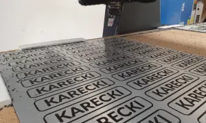 Cięcie CNC na płycie alu dibond z powtarzającym się napisem KARECKI.