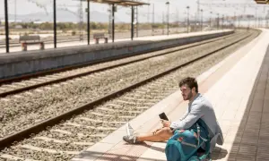 Mężczyzna siedzi na peronie, trzymając telefon. Spóźniłem się na pociąg, co z biletem?