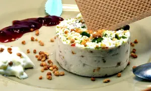 Un délicieux nougat glacé, parsemé de fruits secs et de pistaches, servi avec un coulis de fruits rouges et une touche de crème.
