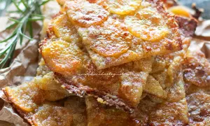 Schiacciata di patate dorata e croccante, con fette sottili di patate e un tocco di rosmarino.