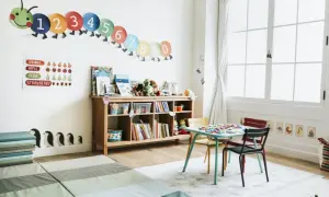 A bright, organized playroom with a number caterpillar, fruit chart, books, toys, and a small table and chairs, perfect for learning and play.