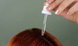 Dłoń z pipetką aplikuje serum na skórę głowy. Idealne rozwiązanie, czym nawilżyć skórę głowy i zadbać o włosy.