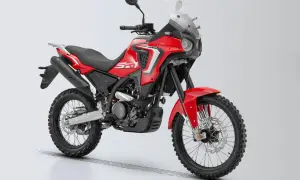 Czerwony motocykl turystyczny z czarnymi oponami terenowymi i dużą szybą.