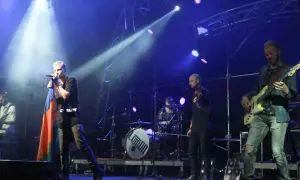 Zespół Lemon na scenie, wokalista z flagą, gitarzysta basowy, perkusja z logo.