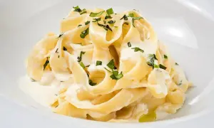 Kremowy makaron tagliatelle z sosem mascarpone i posiekaną natką pietruszki.