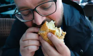 Mężczyzna w okularach je dużego burgera.