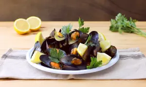 Un piatto invitante di impepata di cozze, guarnito con spicchi di limone fresco e prezzemolo, pronto per essere gustato.