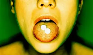 Dwie białe tabletki, przypominające lorazepam, leżą na języku.