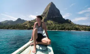 Mann auf Boot vor Bergkulisse in Indonesien. Tolle Reisetipps für dieses Inselparadies!