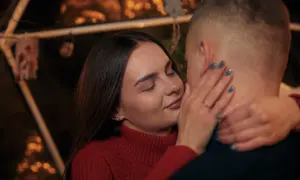 Bliska, intymna chwila pary. Ona zamyka oczy, dotykając jego policzka. Sekret jak rozkochać w sobie faceta na odległość? Bliskość, nawet w oddali.