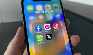 Na ekranie iPhone'a widać folder "Social Media" z ikonami Facebook, Messenger, Instagram, WhatsApp i X. Dowiedz się, jak włączyć powiadomienia Messenger.