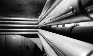 Mehrere Heizungsrohre werden in einem dunklen Raum verlegt. Sie verlaufen parallel und bilden ein komplexes Netzwerk.