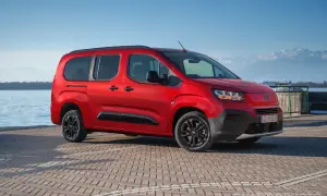 Fiat Qubo rosso fiammante parcheggiato sul lungolago, con montagne innevate sullo sfondo. Le diverse fiat qubo motorizzazioni offrono versatilità.