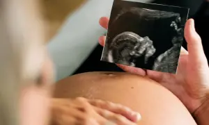 Gravid v 11, en hand håller upp ett ultraljudsfoto av ett foster. Trots oro för missfallsrisk, en stund av hopp.