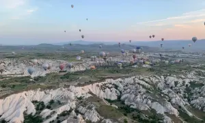 Setki balonów na gorące powietrze unoszą się nad skalistym krajobrazem Kapadocji o wschodzie słońca. To marzenie o podróżowaniu, które można zrealizować, szukając sposobów, jak tanio podróżować.