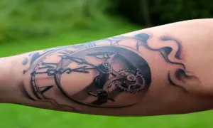 Realistyczny tatuaż zegara na przedramieniu, symbolizujący walkę z czasem i jego nieubłagany upływ.