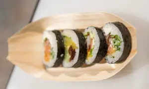 Pięć kawałków sushi z łososiem, awokado i krewetkami na drewnianej łódce. Różne rodzaje sushi nazwy w zasięgu ręki.