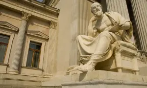 Kamienna rzeźba myśliciela, jak z Psalmu 72, siedzi na tle klasycystycznej budowli.