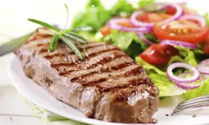 Saftiges Steak mit Grillstreifen und frischem Salat. Perfekt gegart, um zu wissen, wie lange steak im ofen nachgaren muss.