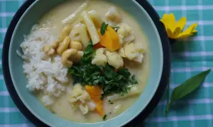 Aksamitny kremowy sos z ryżem, kalafiorem, orzechami nerkowca i marchewką. Pyszne danie inspirowane smakami tajskiej kuchni, przypominające **pasta tom kha**.