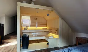 Nowoczesna sauna w domu, z przeszklonymi drzwiami i nastrojowym oświetleniem, idealna do relaksu.