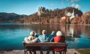Trzech seniorów cieszy się widokiem zamku na skale i jeziora. Idealne wczasy pod gruszą dla emeryta.