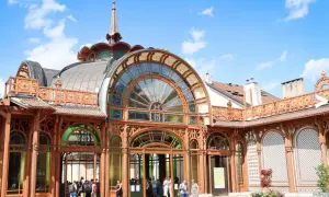 L'architecture Art Nouveau du Palais Lumière à Évian-les-Bains, avec ses vitraux colorés et sa structure en bois, sous un ciel bleu.