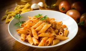 Penne rigate w sosie pomidorowym z parmezanem, ozdobione natką pietruszki. To klasyczne danie, które pokazuje, co to jest penne.